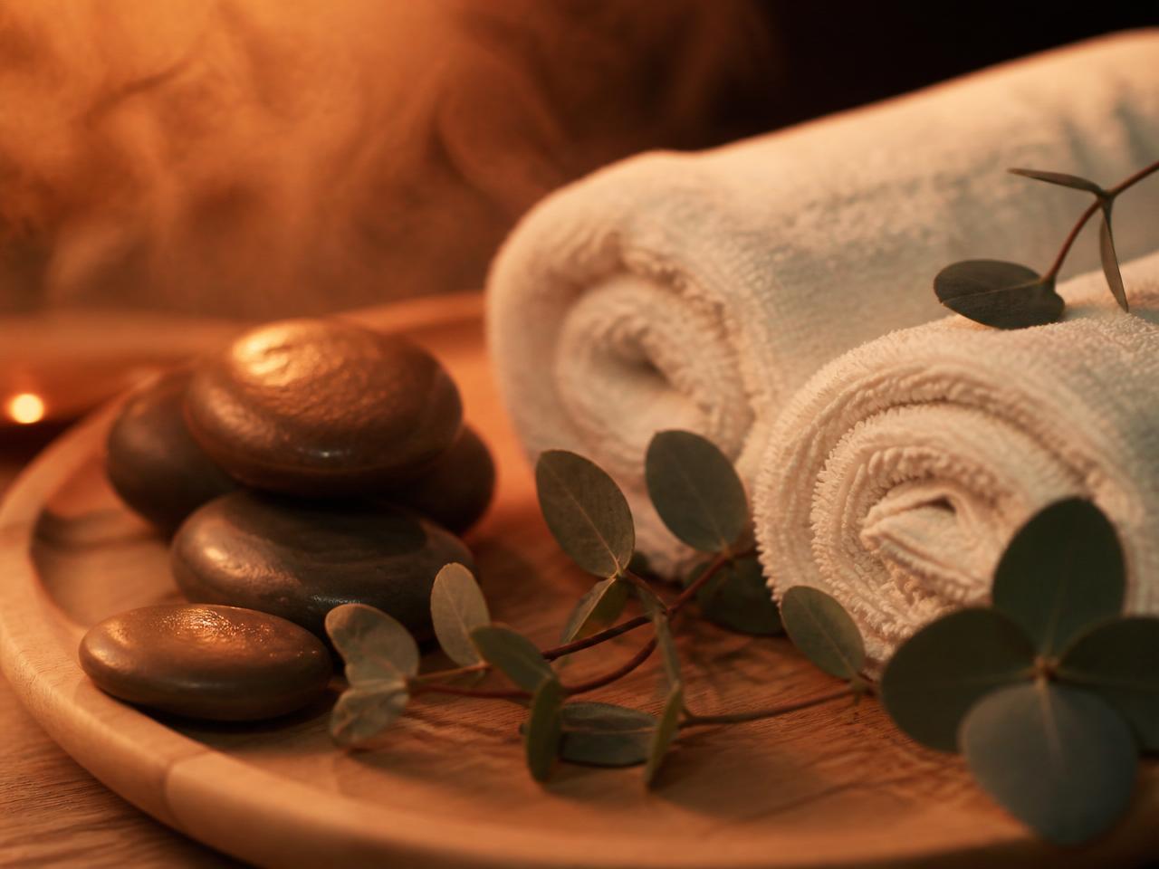 Warm massage stones with eucalyptus on a wooden tray